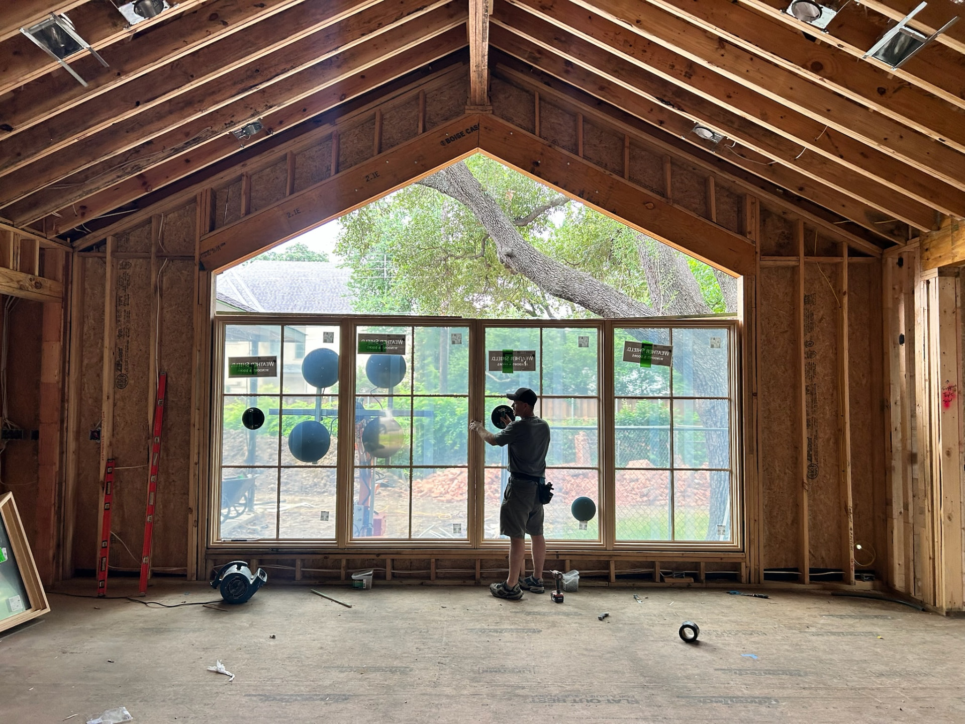 Installer fitting a wide window wall beneath a complex peaked opening