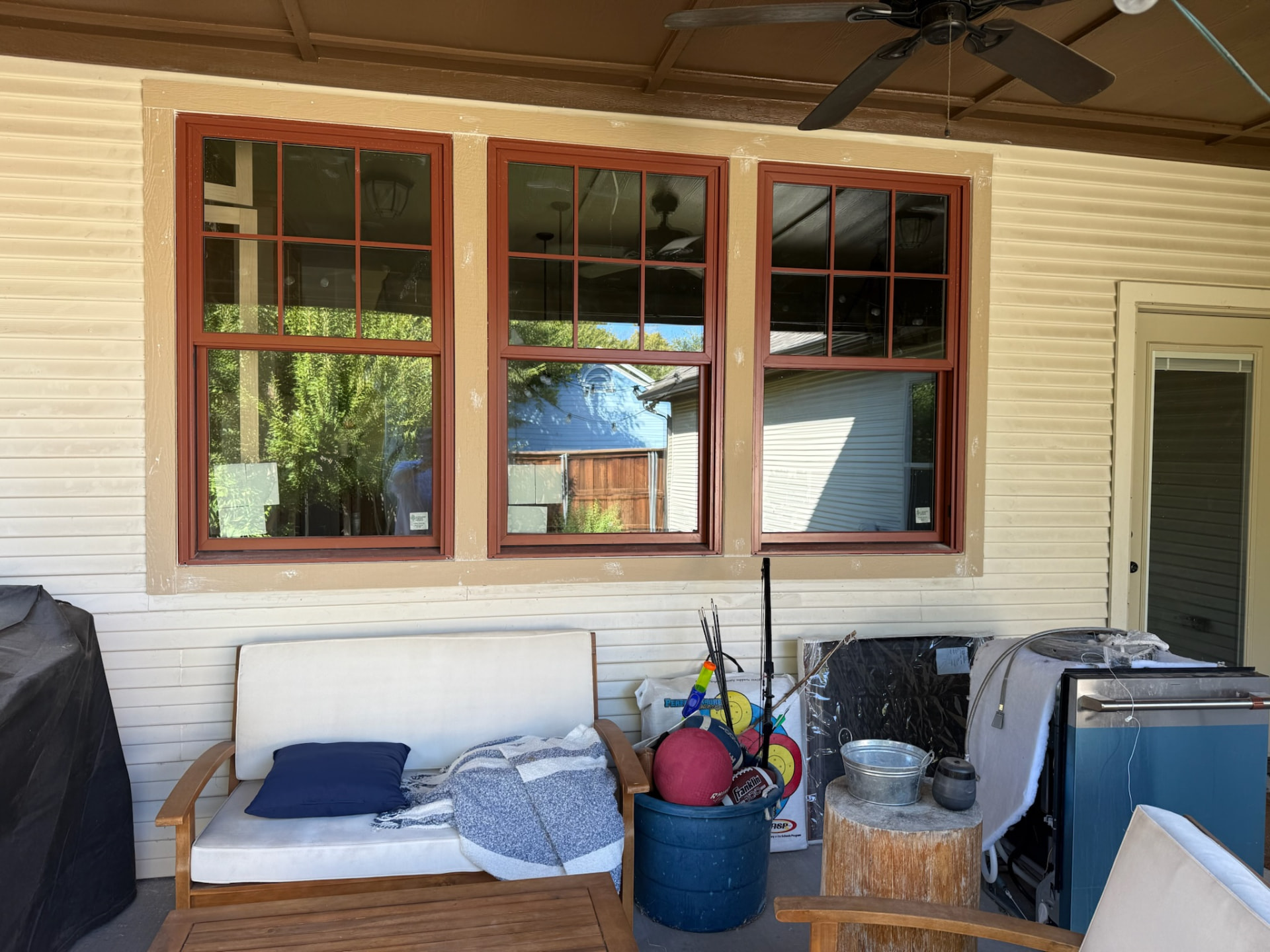 Three red Craftsman-style replacement windows on a covered patio
