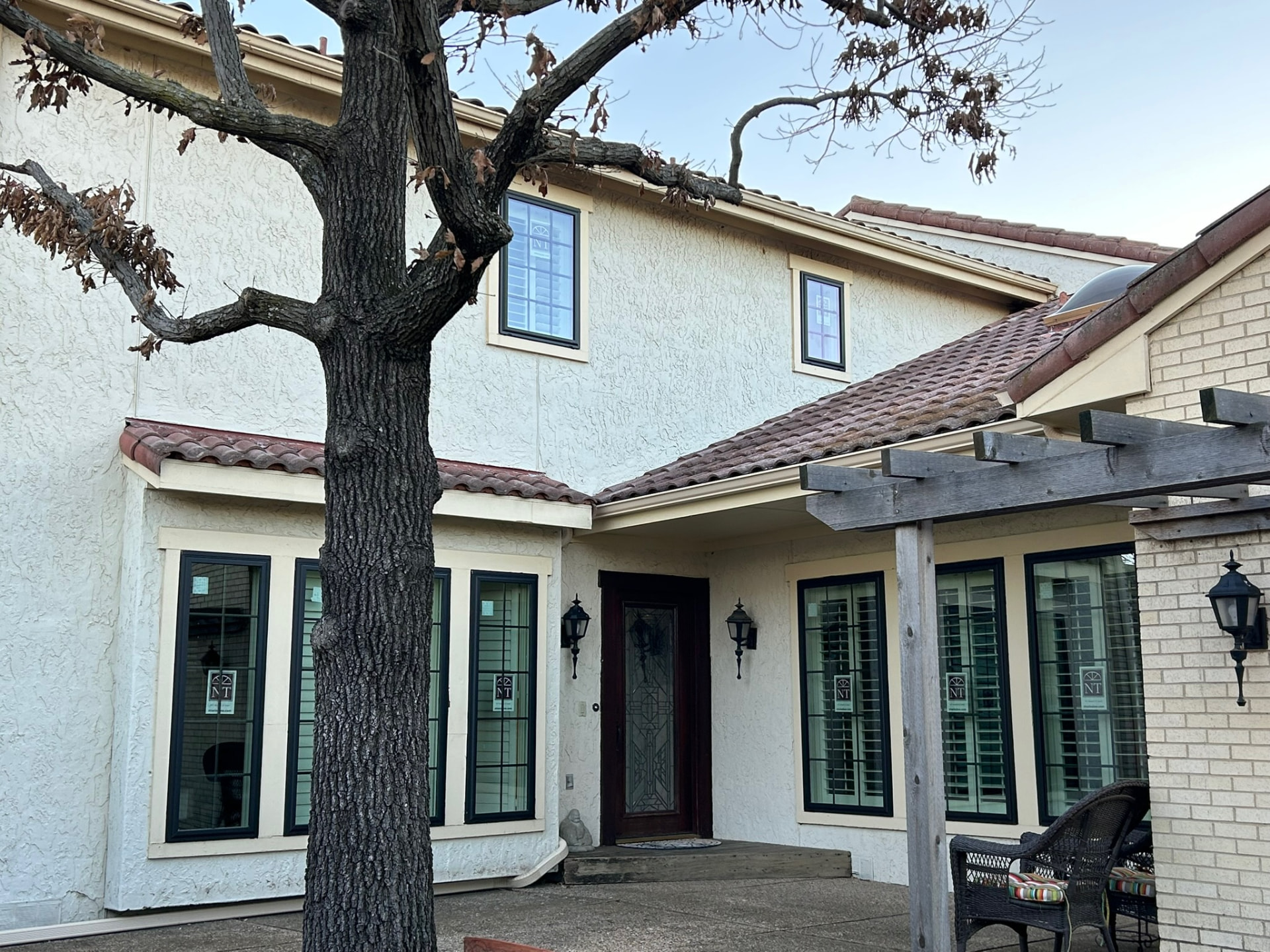 Whole-house replacement windows with dark frames on a stucco home